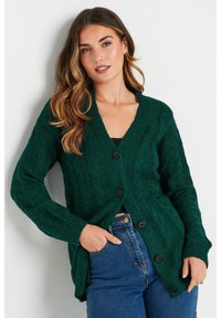 Grön kabelstickad cardigan med djup V-hals, långa ärmar och svarta knappar. Texturen är kraftig och mjuk, med en avslappnad passform.