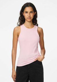 Top sin mangas de canalé en rosa suave, con un escote redondo y un diseño ajustado, combinado con pantalones negros.