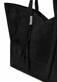 Sac fourre-tout en suede noir avec un design angulaire et net. Présente une anse tressée et des accents de perles argentées. Texture lisse avec un éclat subtil.