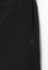 Zwarte sweatpants van zachte stof met een zijzak en een klein reliëflogo op de linkerdij. Glad textuur en een ontspannen pasvorm.