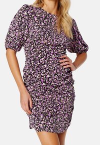 Robe à manches courtes en tissu noir avec un motif abstrait coloré, dotée de détails froncés et d'une silhouette ajustée.