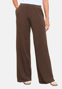 Brūni ribotie platā kāju bikses ar elastīgu jostasvietu. Satur sānu kabatas un teksturētu audumu, paredzēts komfortam un ikdienas valkāšanai.