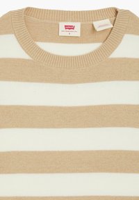 Valkoinen ja vaaleanbeige raidallinen neulepaita, joka on valmistettu pehmeästä neuloksesta. Paidassa on pyöreä kaula-aukko ja ribbireunus. Tunnuksessa on uudeen S-koko ja brändi Levi's.