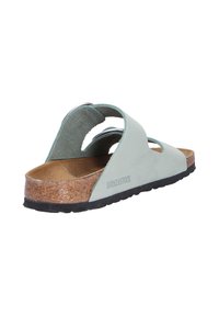 Jasnozielone skórzane klapki z zakrzywionymi paskami, korkową wkładką i gumową podeszwą. Nazwa marki "Birkenstock" wytłoczona z boku.