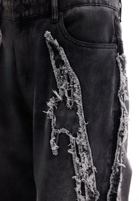 Jean en denim noir avec des motifs de déchirures effilochées et usées le long de la cuisse et près de la poche latérale.