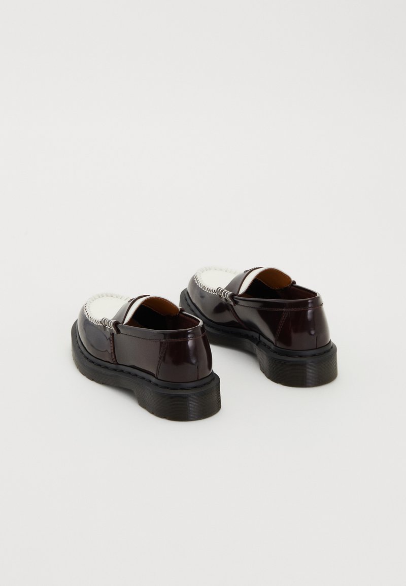 Une paire de mocassins en cuir marron foncé et blanc avec des semelles noires épaisses, présentée sur un fond blanc uni.