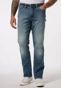 Pantalones de mezclilla de color azul claro con un corte recto, lavado desgastado, diseño tradicional de cinco bolsillos y costuras en contraste. Combinados con zapatillas blancas.