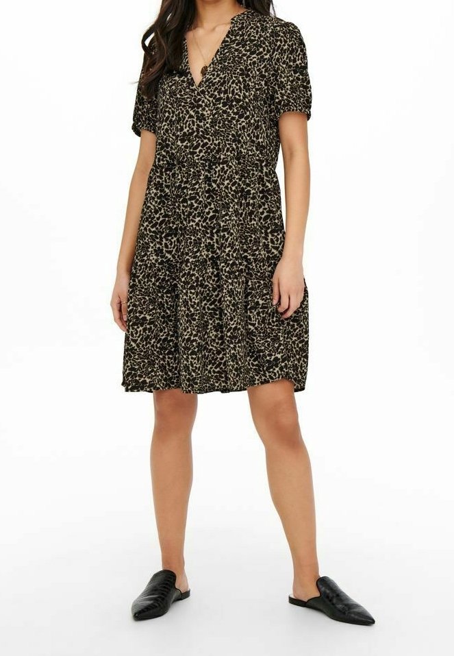 Robe à manches courtes imprimé léopard noir et beige, avec un décolleté en V et une jupe évasée. Associée à des chaussures noires sans lacets.