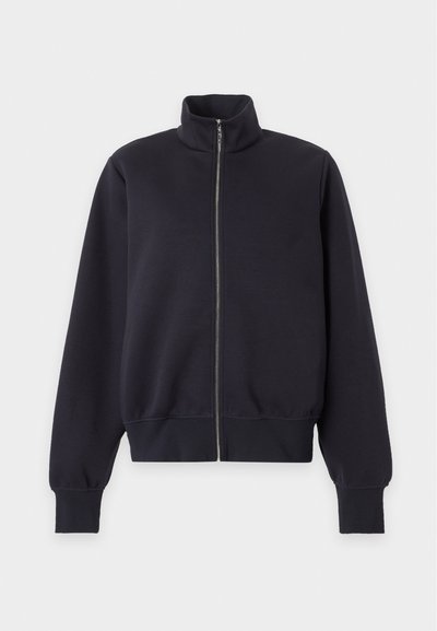 Veste noire zippée avec col montant et manches longues, poignets et ourlet côtelés, présentée sur un fond clair uni.