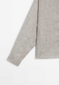 Långärmad grå randig skjorta med ribbade muddar och sidofickor, med en strukturerad tygkvalitet och subtila vertikala ränder.