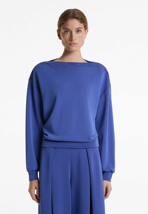 Blue sweatshirt with a wide neckline and long sleeves, featuring a smooth texture and a relaxed fit, paired with matching blue trousers.