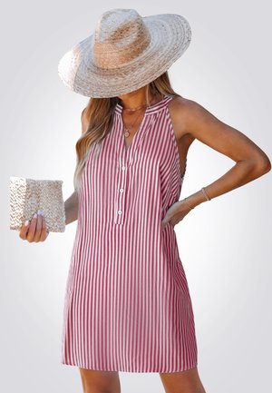 Red and white striped sleeveless dress with a collar, button placket, and side cutouts, paired with a woven clutch and wide-brimmed hat.