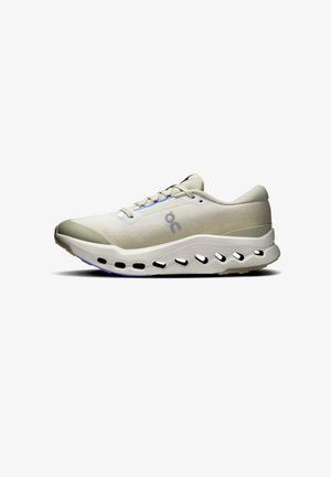 Light beige athletic shoe with a textured upper, laces, and cushioning midsole. Features black and white accents along the outsole.