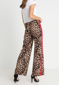 Leopardenmuster-Hosen mit weitem Bein und rotem Seitenstreifen, aus weichem Stoff gefertigt, mit lockerer Passform und elastischem Bund.