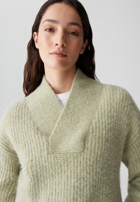 Strickpullover in Hellgrün mit strukturiertem, geripptem Muster. Verfügt über einen breiten, überlappenden Kragen und eine lockere Passform.