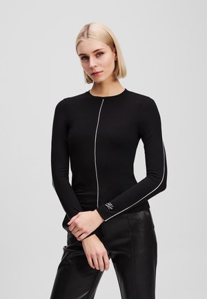 Maglia nera a maniche lunghe con scollatura rotonda, cuciture bianche a contrasto e branding minimale sui polsini. Tessuto liscio e aderente.