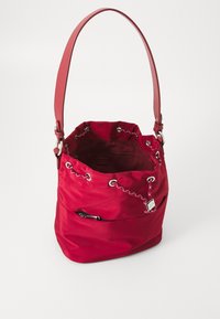 Piros nylon vödör táska levehető vállpánttal, összegyűjtött tető ezüst lyukakkal, és belső zsebbel. Simás text�úra, lezser dizájn.