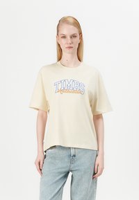 Lichtbeige T-shirt met korte mouwen van katoen, met "TIMBS" in het blauw en "Authentic" in oranje cursief. Ontspannen pasvorm, ronde halsdesign.