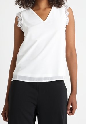 Débardeur blanc sans manches avec un décolleté en V et des accents en dentelle sur les coutures des épaules, présentant un tissu lisse et une coupe décontractée.