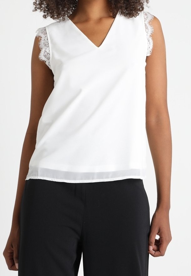 Débardeur blanc sans manches avec un décolleté en V et des accents en dentelle sur les coutures des épaules, présentant un tissu lisse et une coupe décontractée.