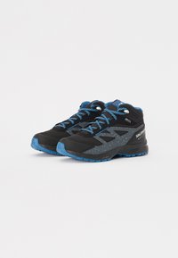 Zapatos de senderismo negros y grises con acentos azules, tela texturizada y diseño moteado. Cuentan con cordones redondos y una suela resistente para proporcionar tracción.