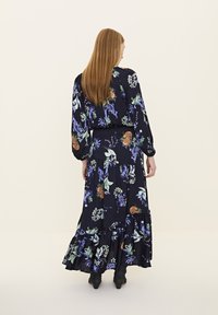 Maxikleid mit floralen Motiven aus navyblauem Stoff, langen Ärmeln, gestuften Rüschen und mehrfarbigen botanischen Drucken. Es hat eine taillierte Taille und eine fließende Silhouette.