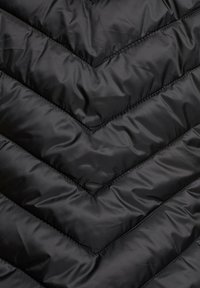 Tissu noir matelassé avec des coutures en forme de chevrons et une texture légèrement brillante et rembourrée.
