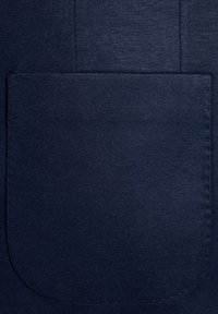 Granatowy materiał z dużą kieszenią naszywaną, gładką teksturą oraz widocznymi szwami i detalami. 