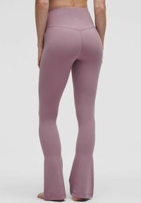 Testre szabott, magas derékú jóga nadrág világos mályvaszínben, harang alsó résszel és varrás nélküli kialakítással. Puha, rugalmas anyagból készült a kényelmes viselet érdekében.
