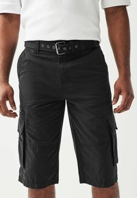 Sorte cargo shorts med flere sidelommer, glat front og et sort bælte med metalhardware. Fremstillet af letvægtsstof med en glat tekstur.
