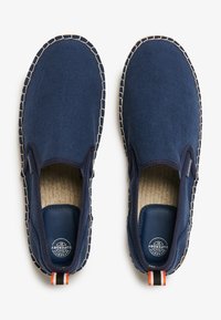 Zapatillas de lona navy con detalle de yute trenzado a lo largo de la suela, interior navy y una etiqueta multicolor en el talón.