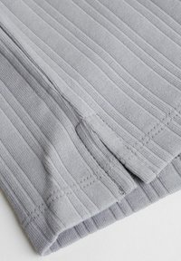 Grå ribbad tyg med en texturerad yta, med en rak nederkant och synliga söms detaljer. Mjukt och lätt material.