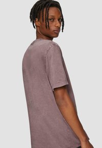 T-shirt met korte mouwen en ronde hals in gedempt paarse katoenstof met een vervaagde textuur. Heeft een ontspannen pasvorm en lichtgerolde mouwen.