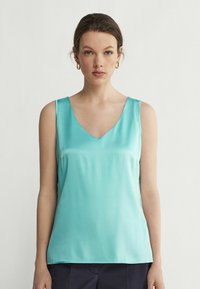 V-ringad, ärmlös topp i klar turkos satin. Slät textur med en avslappnad passform, framhävd av en minimalistisk design.