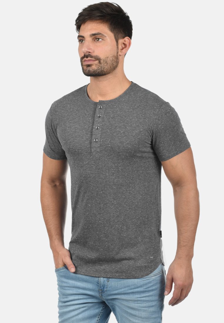 Grå kortærmet Henley skjorte lavet af en struktureret bomuldsblanding, med en tre-knaps knaplukning og en lige kant. Båret med lyseblå jeans.