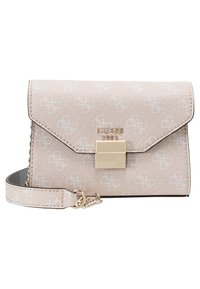 Beżowy portfel na nadgarstek Guess 1981 z białym wzorem monogramu, złotym zapięciem oraz pasującym paskiem z złotym łańcuchem.