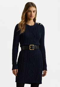 Abito maglione blu navy con motivi a treccia, maniche lunghe e bottoni sulle spalle. Presenta una cintura nera con un accento di fibbia dorata.