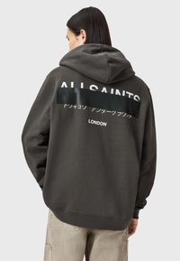 Dunkelgrauer Hoodie mit Kängurutasche, versehen mit großen weißen Schriftzügen "ALL SAINTS" und weiteren Druckdetails auf der Rückseite. Weicher Stoff.