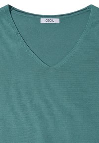 Pull en maille bleu sarcelle à col en V avec un motif finement texturé et une étiquette de marque "CECIL" cousue à l'intérieur du col.