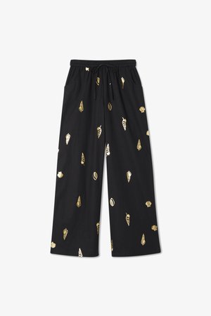 Black wide-leg pants with an elastic waistband and drawstring, featuring metallic gold leaf patterns throughout. Smooth texture, casual design.