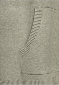 Sudadera gris con un bolsillo acanalado, textura suave y puños acanalados. La tela parece lisa con un ligero estiramiento y un diseño minimalista.
