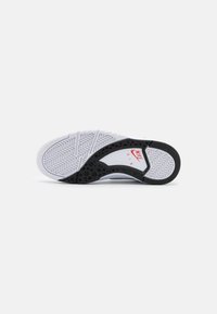 Nike shoe sole with a predominantly white design, featuring a black accent and textured tread pattern. Red Nike logo near heel area.