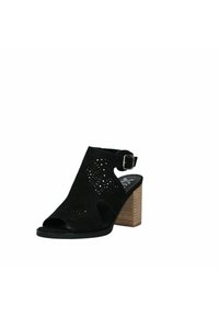 Sandal in suede nero aperto con design a ritaglio, cinturino alla caviglia e tacco quadrato in legno. Presenta una finitura testurizzata e una suola imbottita.