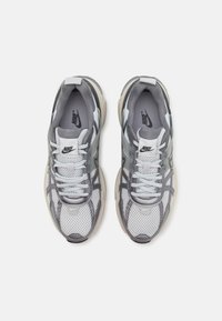 Tenisky Nike s horní částí z lehké šedé síťoviny s tmavšími šedými akcenty, bílými tkaničkami a strukturální gumovou podrážkou pro trakci.