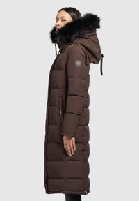 Bruine pufferjas met een zwarte nepbontcapuchon, een quiltpatroon, ritsluiting en zijzakken, met een logo-opdruk op de mouw.