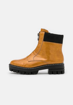 Glossy orange leather ankle boot with black suede accent, side zipper, and rugged black sole featuring deep lugs for enhanced grip.