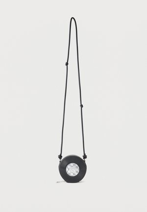 Zwarte ronde crossbodytas met verstelbare band en monochroom geometrisch ontwerp in het midden, afgebeeld op een witte achtergrond.