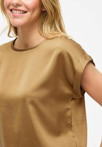 T-shirt à manches courtes en satin de couleur marron clair, avec un col rond et une texture douce et lisse, dotée de manches retournées et d'entailles sur les côtés.