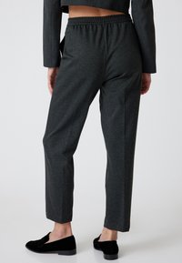 Pantalons gris à coupe décontractée avec une taille élastique, longueur cheville, fabriqués dans un matériau doux, présentant une texture lisse et sans motifs visibles.