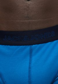 Κοντινό πλάνο σκοτεινόχρωμου ατόμου που φορά μπλε εσώρουχα Jack & Jones με σκούρη μπλε μέση και ορατά ραφές.